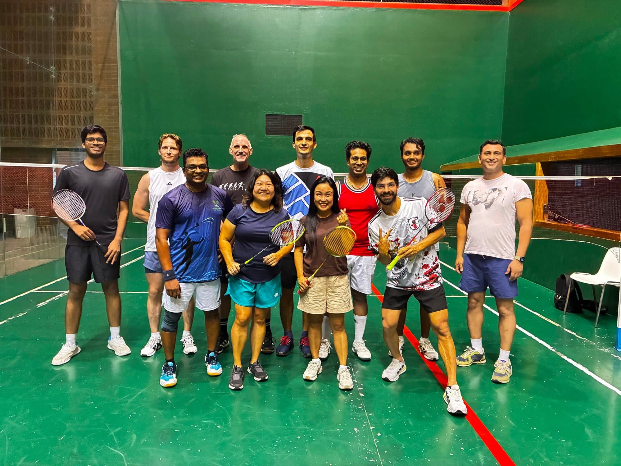 Keep Calm Community Barcelona badminton group posing with rackets on an indoor court after a session
