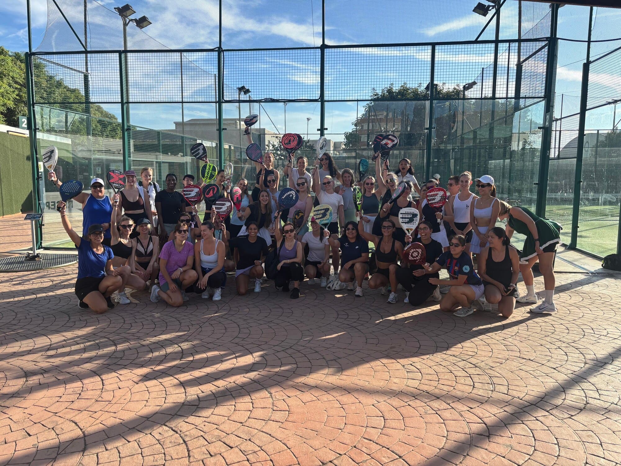 Large group of women celebrating with padel rackets raised after a Women's Padel Americana session at Pàdel Delfos, Keep Calm Community Barcelona