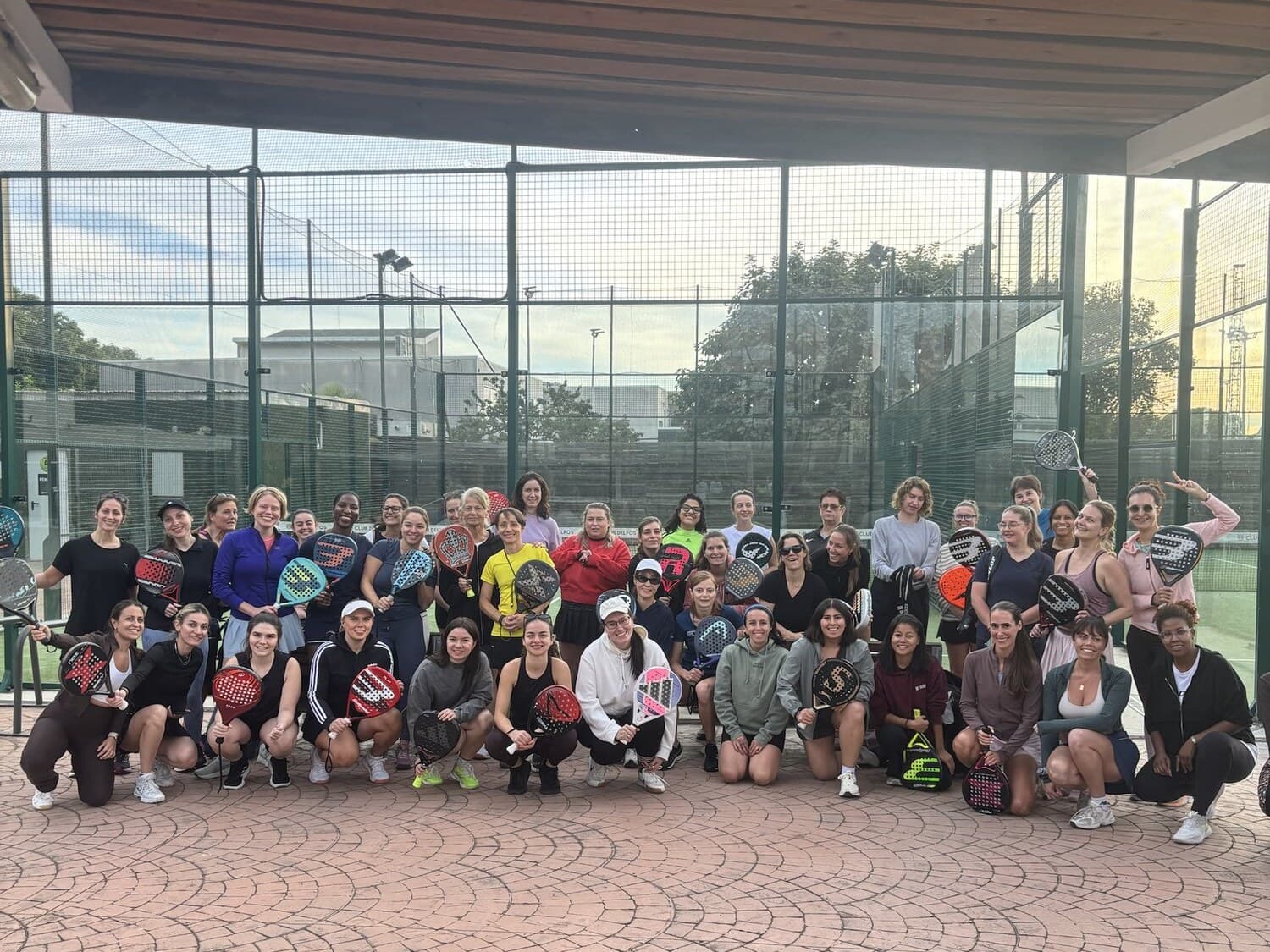 Women's Americana players smiling with their padel rackets on the terrace at Pàdel Delfos, Keep Calm Community Barcelona
