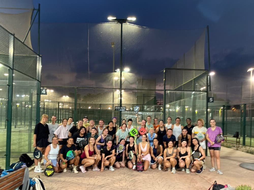 Large group of women with padel rackets gathered on court at night after a Women's Americana in Barcelona