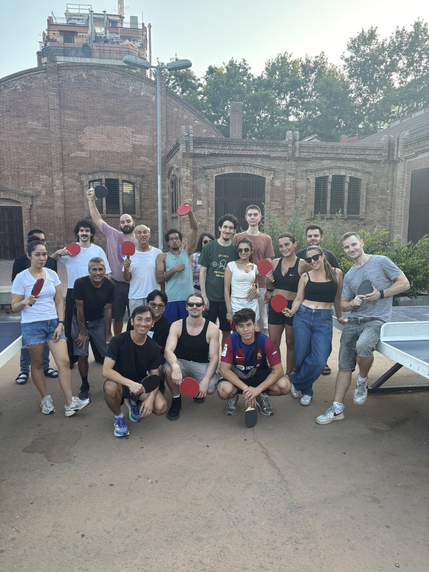 Large Keep Calm Community group photo holding table tennis paddles at Thursday session in Sants, Barcelona