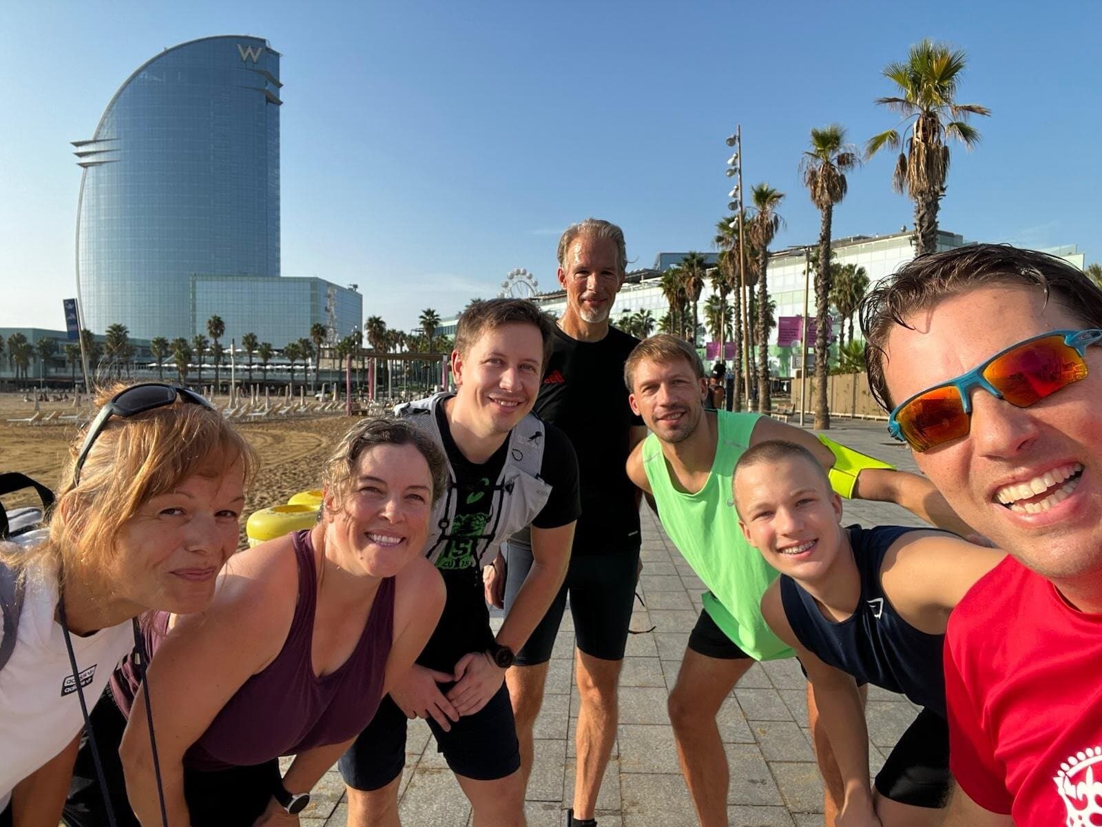Keep Calm Community Barcelona runners smiling together on the Barceloneta beachfront promenade with the W Hotel in the background