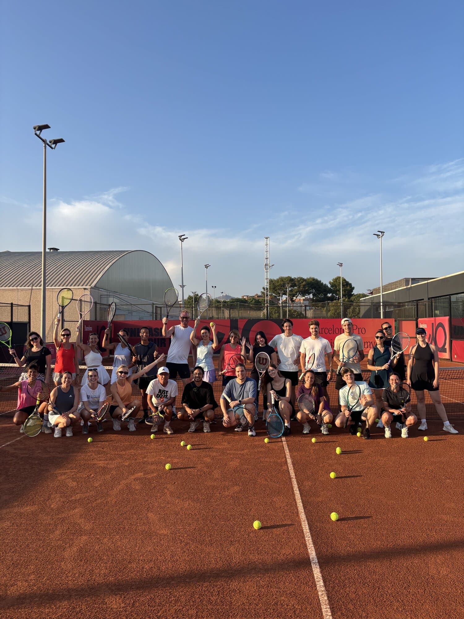 Large Keep Calm Community group lined up on the clay courts before Tuesday tennis at Up Cornellà