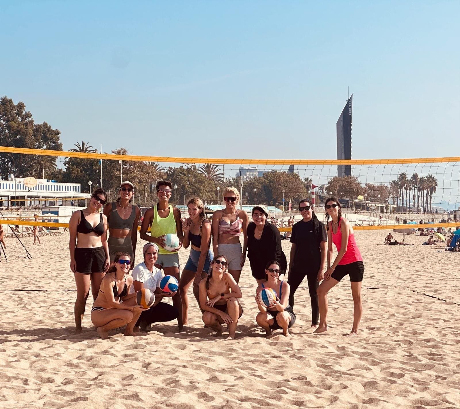Group of women posing with volleyballs at a beach volleyball court in Barcelona, Keep Calm Community Barcelona